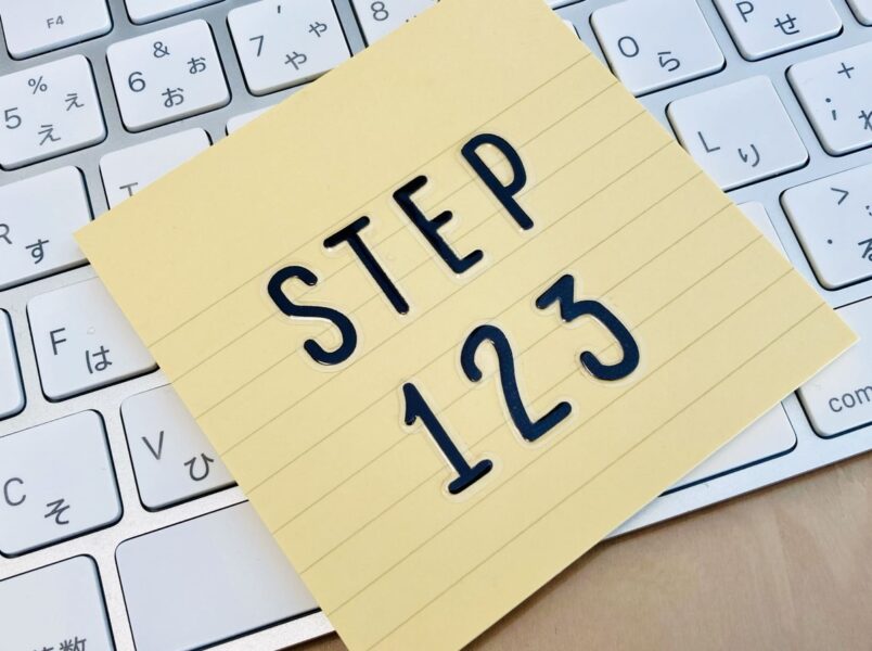 「STEP 123」と書かれた黄色いメモ用紙がキーボードの上に置かれている画像。バーチャルオフィスの提供サービスを順序立ててわかりやすく解説する流れを象徴している。