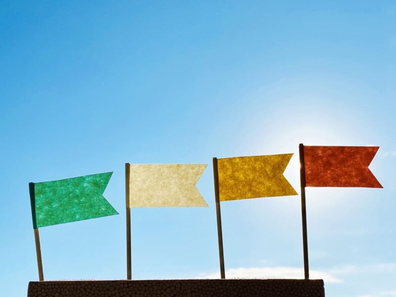 「法人登記可能で格安だけどサービスのバランスがよいバーチャルオフィスのランキングを象徴するイメージ画像。青空を背景に、緑、黄色、オレンジの旗が掲げられており、ランキング上位を示唆している。