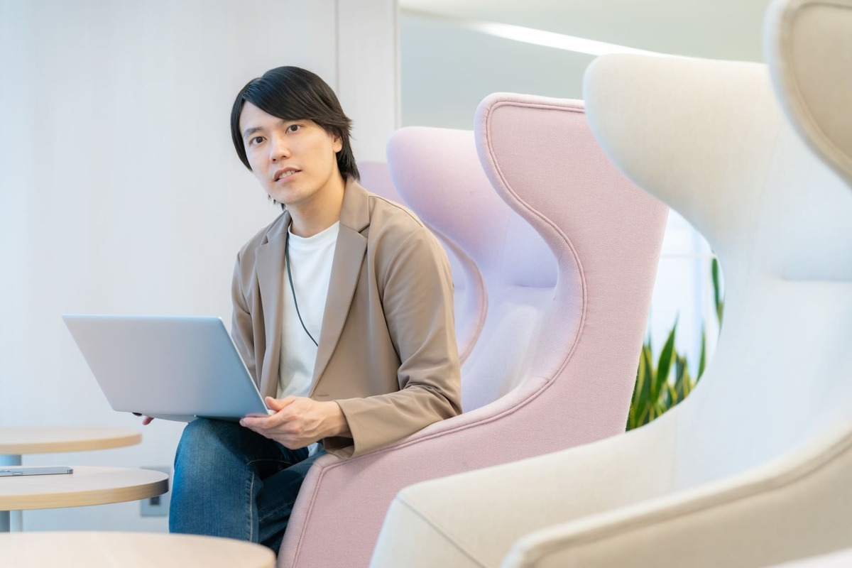 「METSバーチャルオフィス解約時の注意点を解説するページのイメージ画像。ラウンジチェアに座り、ノートパソコンを持ちながら考え事をしているビジネスパーソン。スマートに解約手続きを検討しているシーンを象徴。