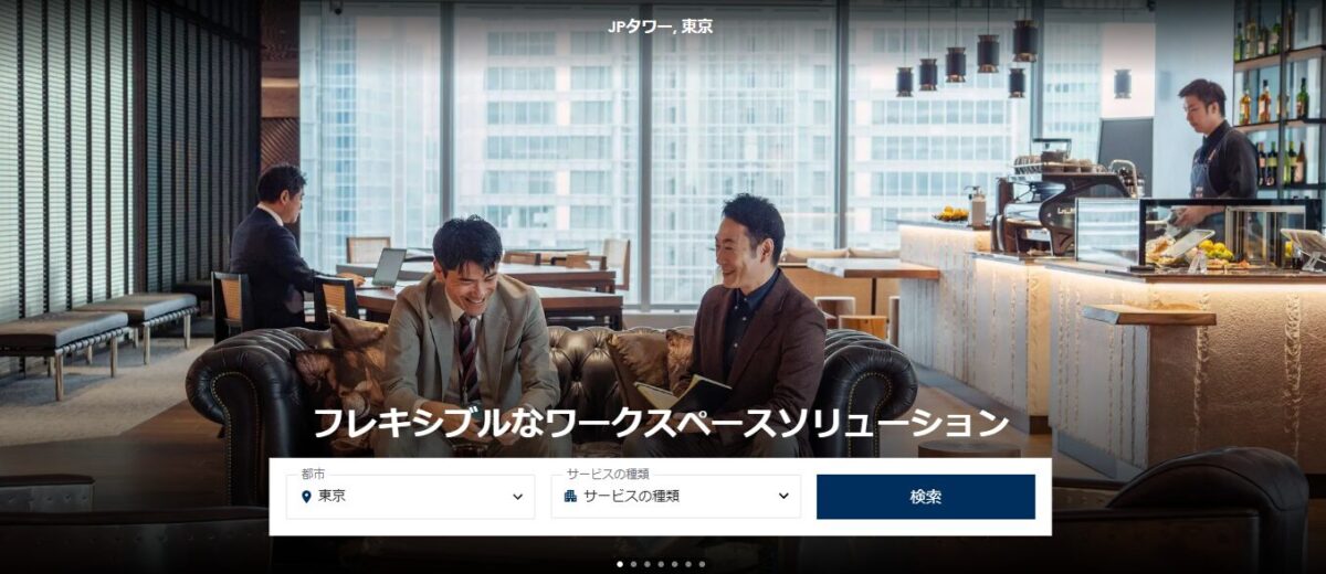 THE EXECUTIVE CENTER(TEC)のPR画像。高層ビル内の洗練されたカフェスペースでビジネスミーティングを行う利用者の様子を通じて、プレミアムなワークスペースと柔軟なビジネス環境を訴求している。