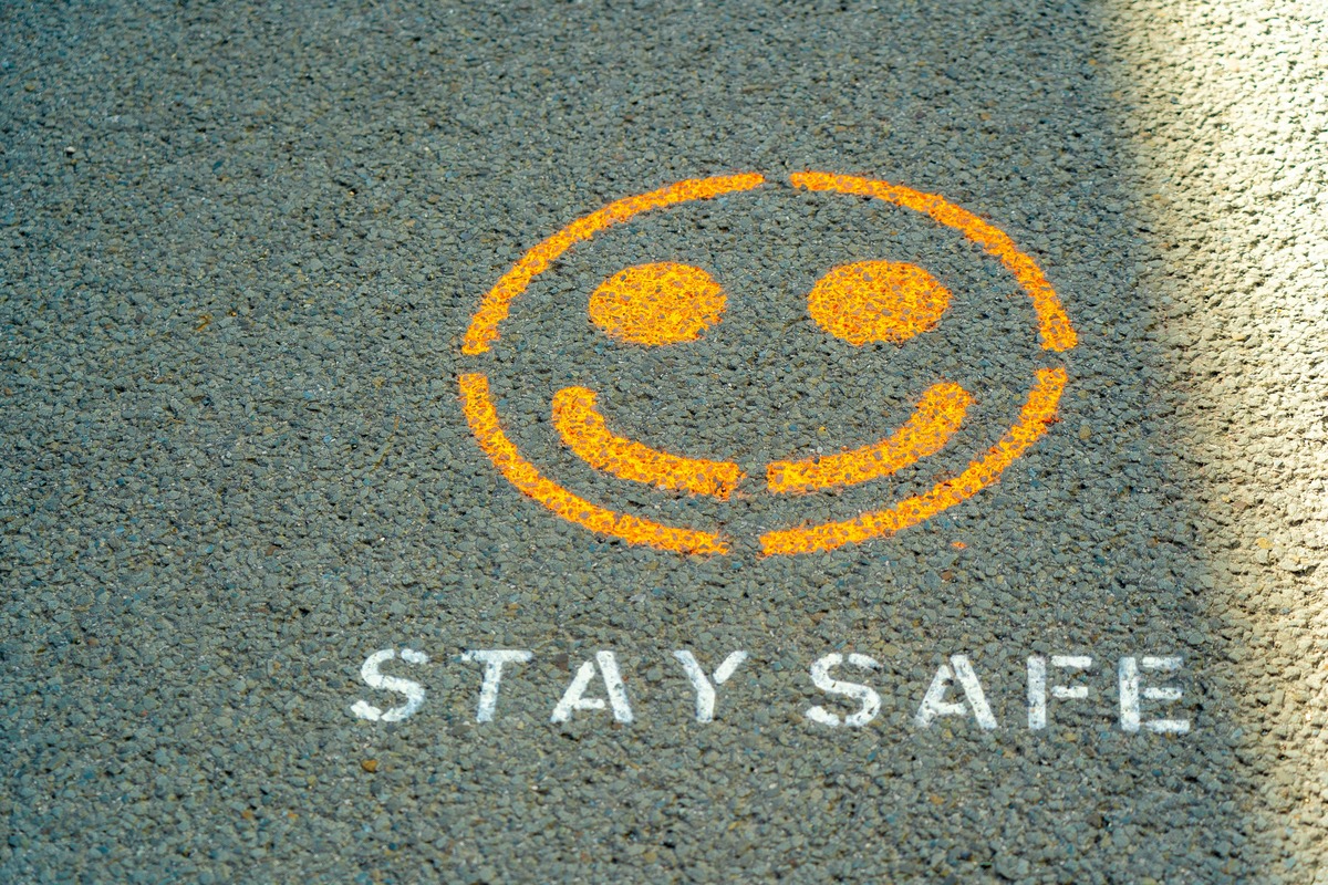 アスファルト上に描かれたオレンジ色のスマイルマークと「STAY SAFE」の白い文字。DMMバーチャルオフィス解約前に注意すべきポイントの確認を象徴するビジュアル。